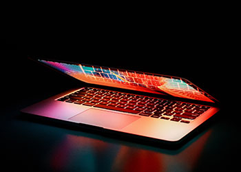halb geöffneter Laptop im Dunkeln mit bunten Farben
